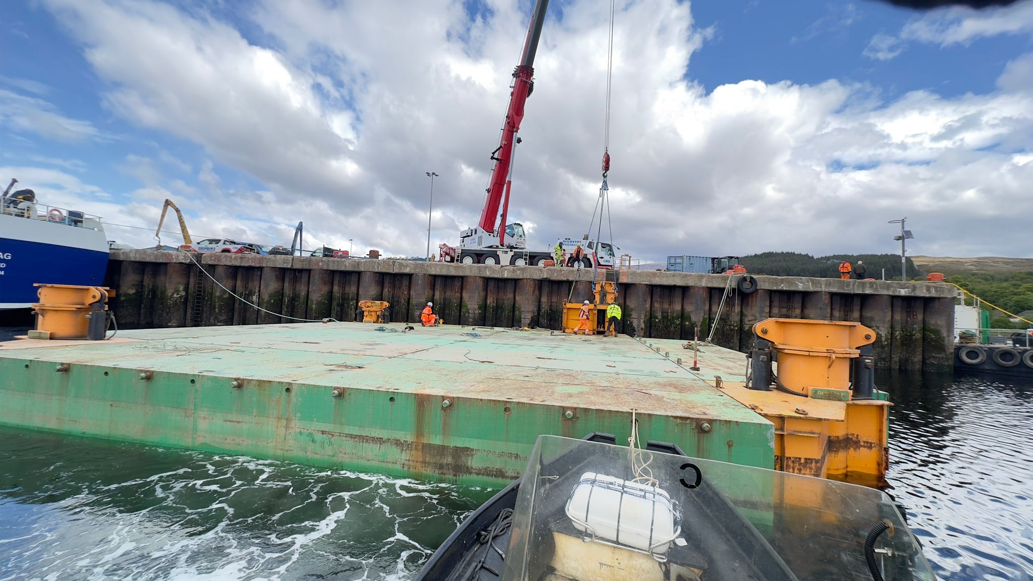 Jack-up platform with a crane and workers beside a quay
